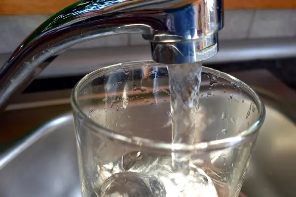 GLas unter Wasserhahn