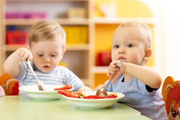 zwei Kleinkinder am Tisch mit Essen