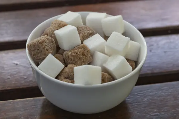 Weiße und braune Zuckerwürfel in einer weißen Schüssel.