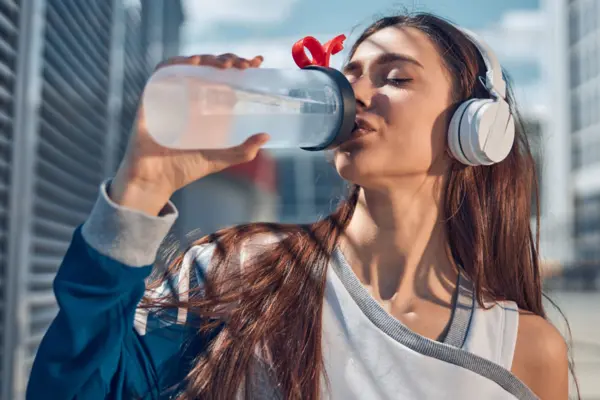 Eine Frau trinkt Wasser aus einer Getränkeflasche
