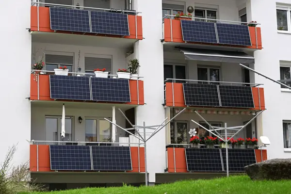 Hausfront mit mehreren Balkonen mit Steckersolarmodulen