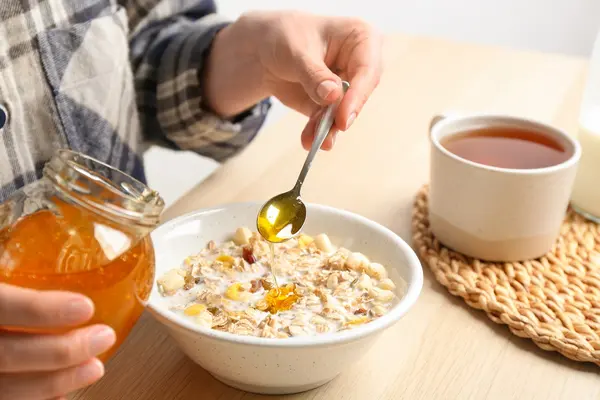 Eine Frau macht Honig in ihr Frühstück.