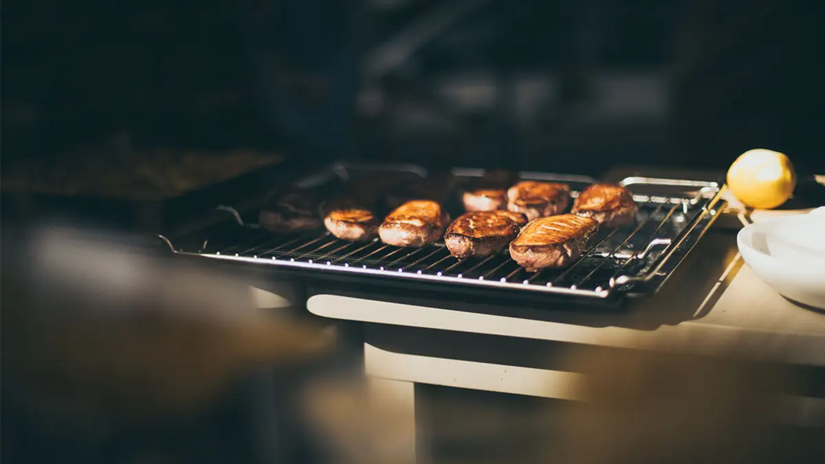 Von der Sonne beschienener Grill, auf dem gegrilltes Fleisch liegt
