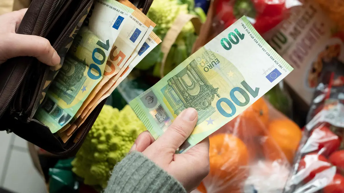Jemand bezahlt mit einem 100 Euro Schein Waren an der Supermarktkasse. Blick von oben ins Portmonnaie