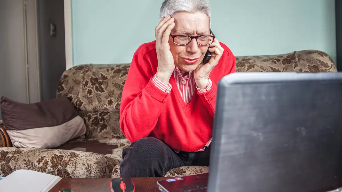 Seniorin ärgert sich am Telefon und Laptop