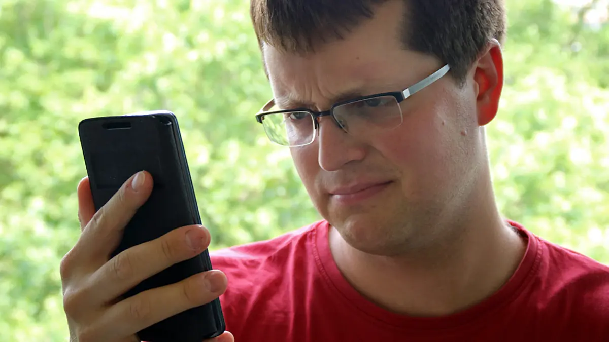 Mann schaut befremdet auf Smartphone