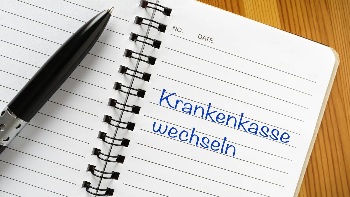 Jemand hat die Wörter "Krankenkasse wechseln" in einen Notizblock geschrieben