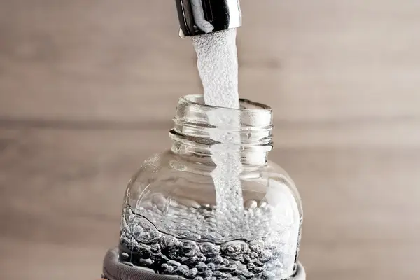 Ein Wasserhahn, aus dem Wasser in eine Flasche fließt.