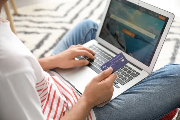 Ein Mann bucht einen Flug am Laptop und benutzt dafür eine Kreditkarte