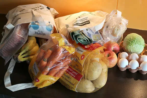 Zwei volle Einkaufsbeutel mit Lebensmitteln liegen auf einer Küchenarbeitsplatte.