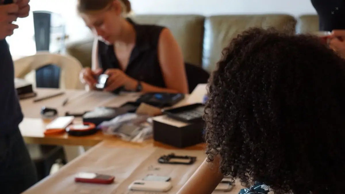 Menschen sitzen an einem Tisch und reparieren Smartphones und andere elektronische Geräte