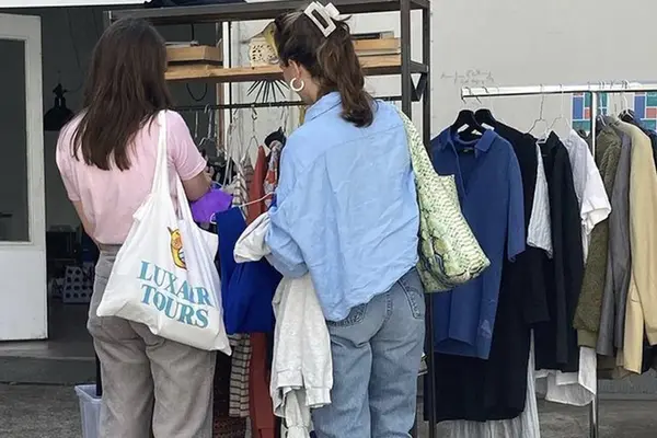 Zwei Frauen stehen an einem Kleiderständer auf einer Kleidertauschparty