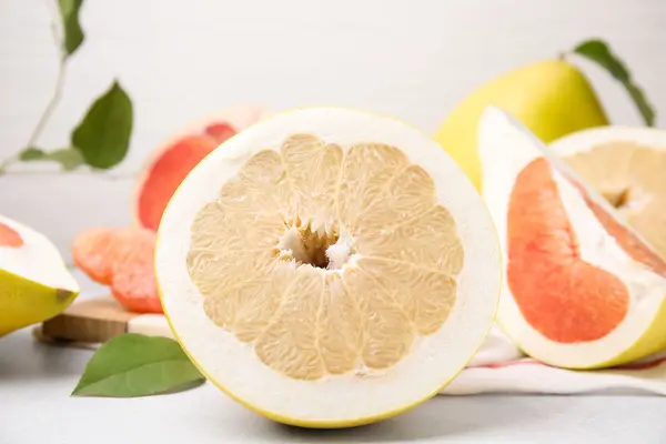 Halbierte Pomelos liegen auf einem weißen Tisch.