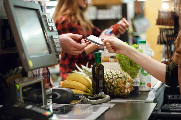 Kasse im Supermarkt, Waren auf Laufband, Kunde bezahlt