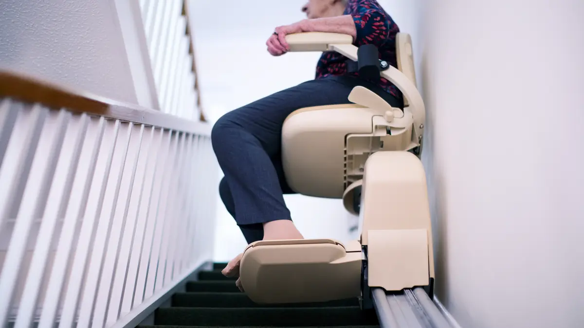 Ältere Frau sitzt auf einem Treppenlift