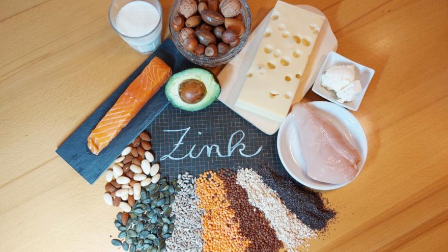 Verschiedene Lebensmittel, die Zink enthalten, sind um eine Tafel gruppiert, auf der das Wort Zink steht.