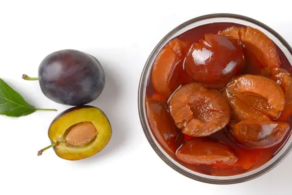 Pflaumen und eine Schale mit Pflaumenkompott