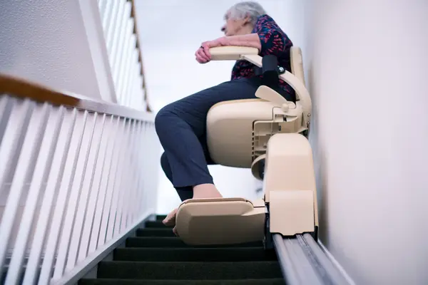 Ältere Frau sitzt auf einem Treppenlift