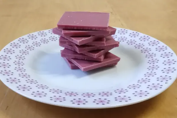 Gestapelte Stückchen Ruby-Schokolade auf einem Teller.