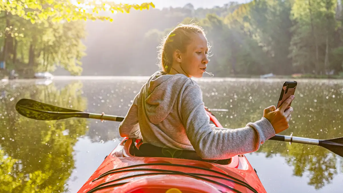 Frau sitzt in einem Paddelboot und macht ein Foto