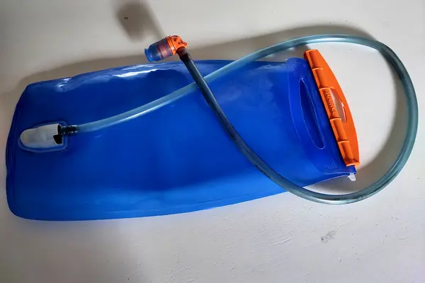 Eine blaue Trinkblase mit Schlauch liegt auf einem Tisch.