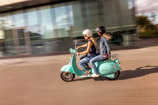 Zwei Frauen mit Helm auf einem E-Roller E-Scooter