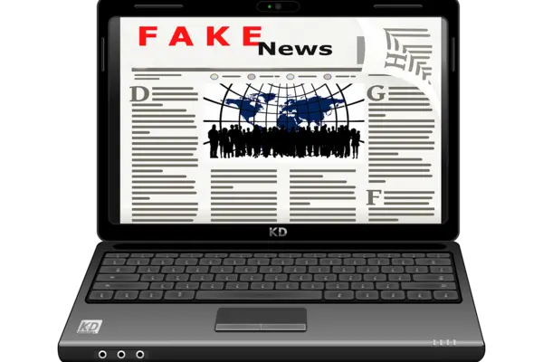 Auf dem Bildschirm eines aufgeklappten Laptops ist das Wort Fake News zu lesen