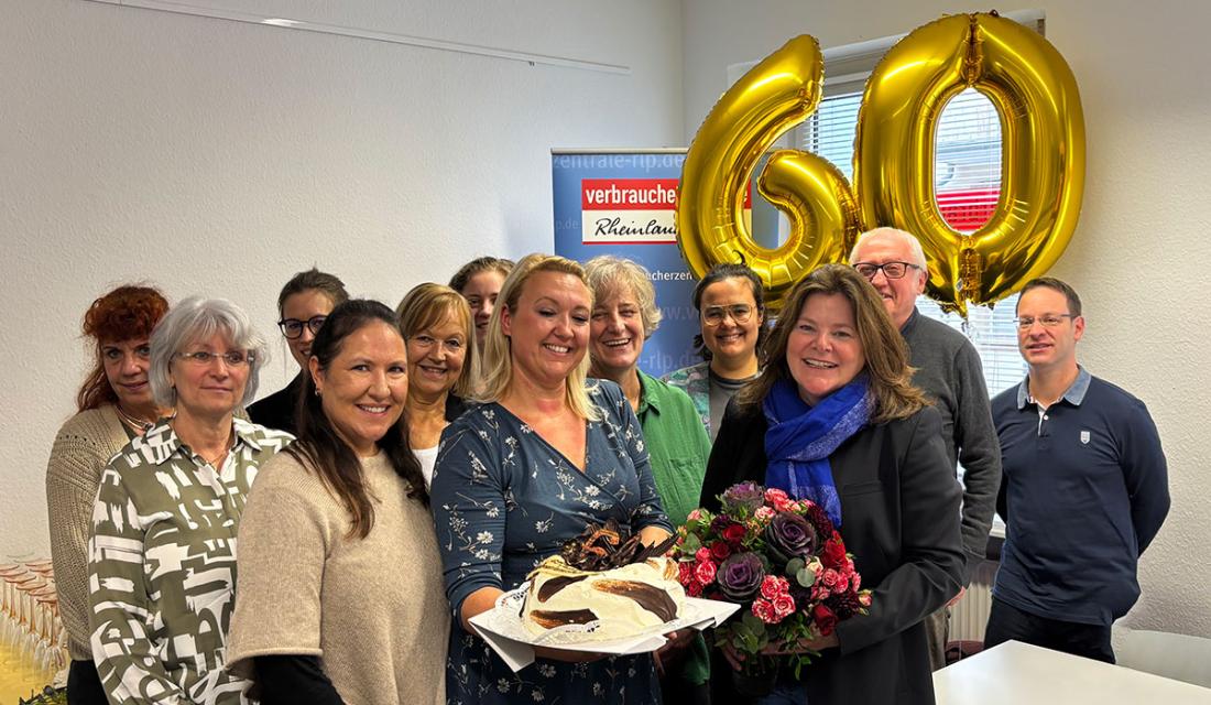 Eine Gruppe aus fröhlichen Menschen, die einen Kuchen in die Kamera halten