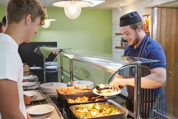 Koch portioniert Essen auf Teller