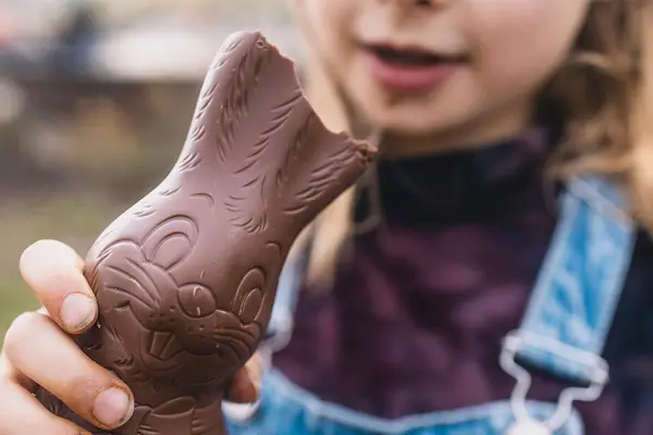 Mädchen hält angebissenen Schoko-Osterhasen