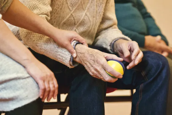 älterer Mensch hält einen Ball