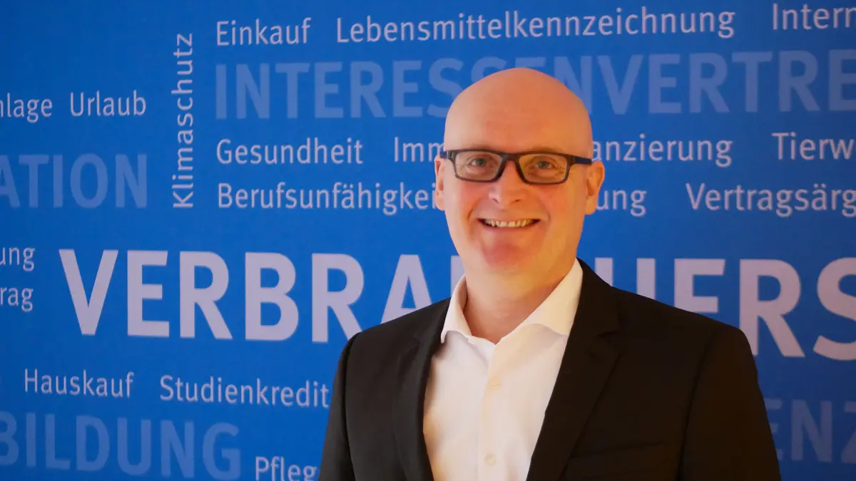 Stefan Bock, Vorstand der VZSH, Porträt vor blauer Wand