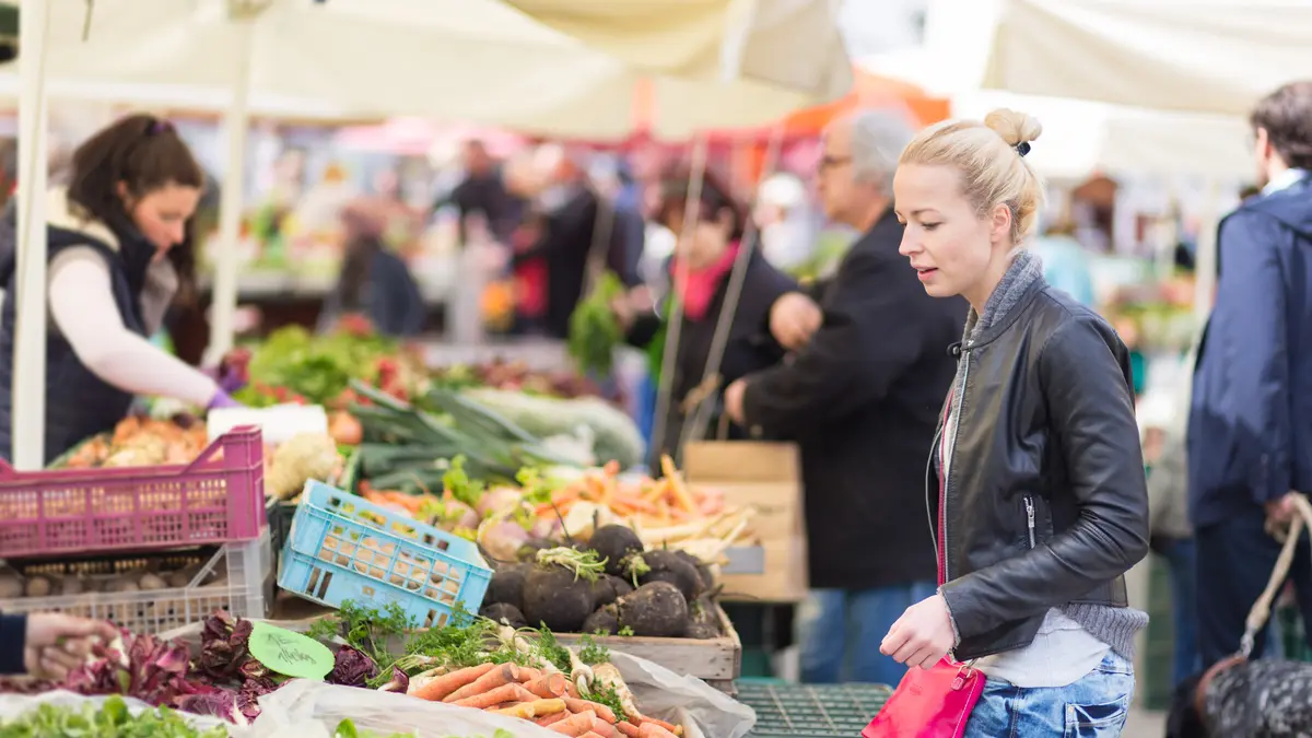 Frau kauft an einem Marktstand ein