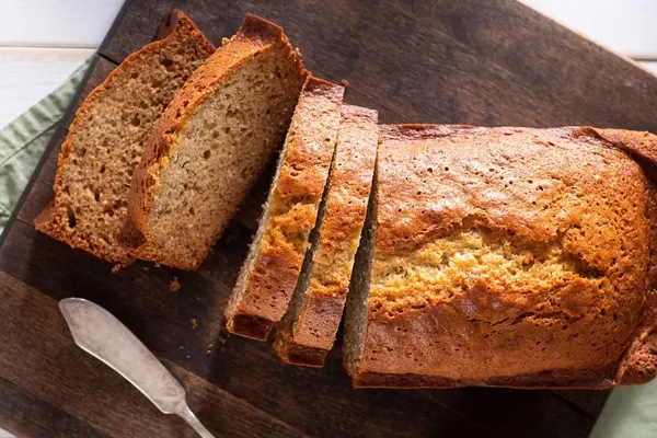 Bananenbrot liegt geschnitten auf einem Holzbrett