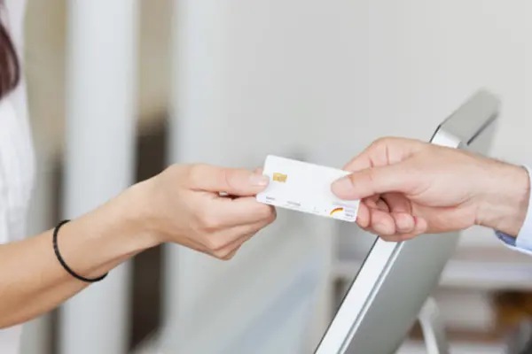 Übergabe einer Chipkarte (Krankenkassenkarte) am Praxisempfang.