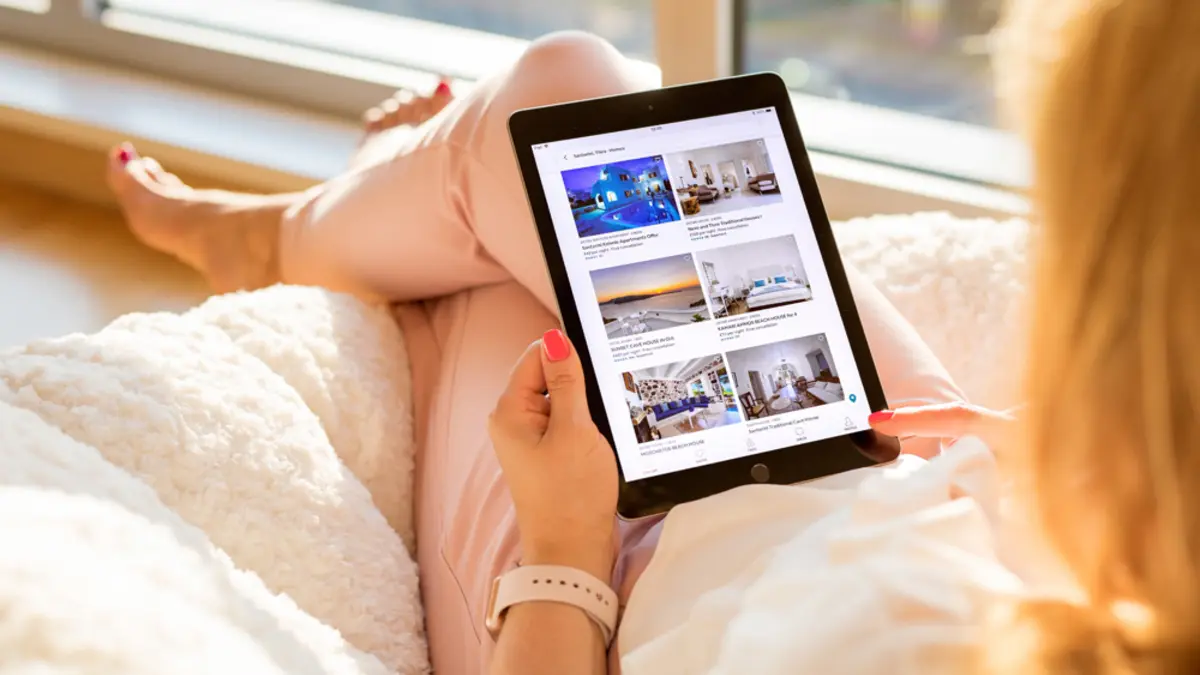 Frau schaut auf Website Buchungsportal mit Tablet