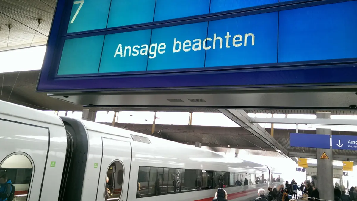 Ein ICE steht an einem Bahnhofsgleis mit der Anzeige "Ansage beachten"