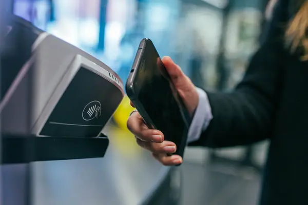 Ein Kunde hält sei Smartphone zum Bezahlen an Gerät zum kontaktlosen Bezahlen