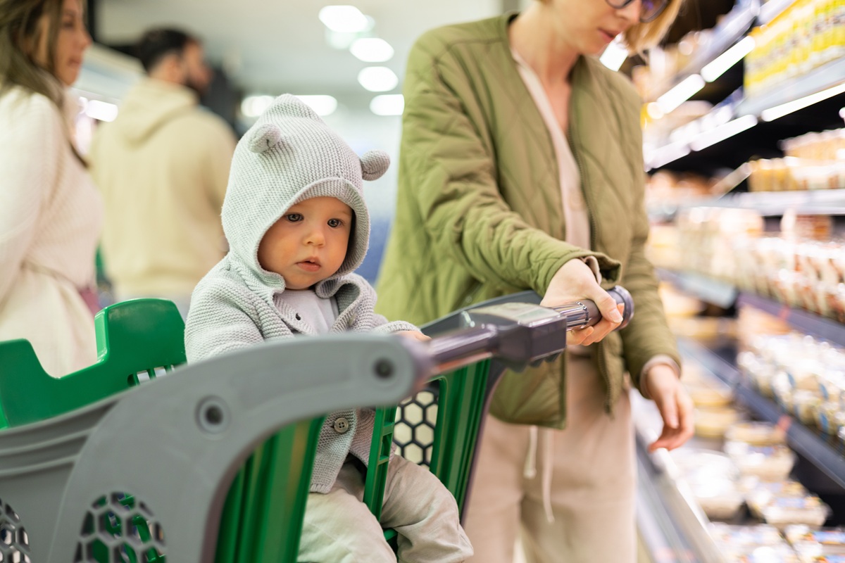 Ein Baby sitzt in einem Einkaufswagen im Supermarkt.