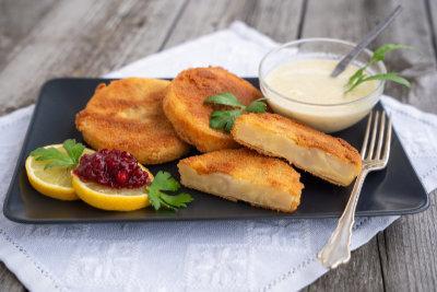 Gebratene Sellerieschnitzel auf einem Teller mit Dip in einer Schale und Zitronenscheiben