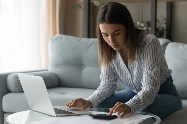 Studienkredit: Eine Studierende rechnet ihre Finanzen mit Laptop und Taschenrechner durch.