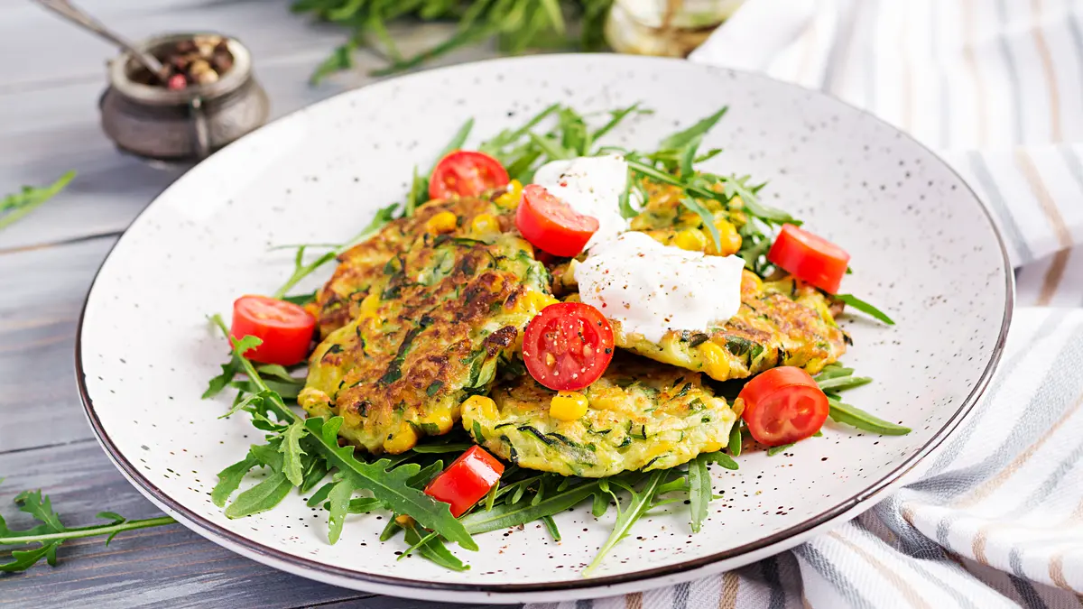 Zucchini Pfannkuchen mit Rucola und Tomaten garniert auf einem Teller