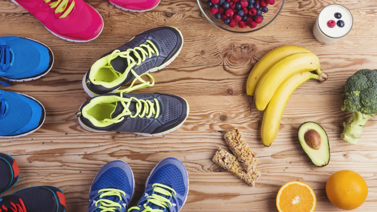 mehrere Paare Turnschuhe stehen vor Bananen, Avocado, Müsliriegeln und anderen Lebensmitteln