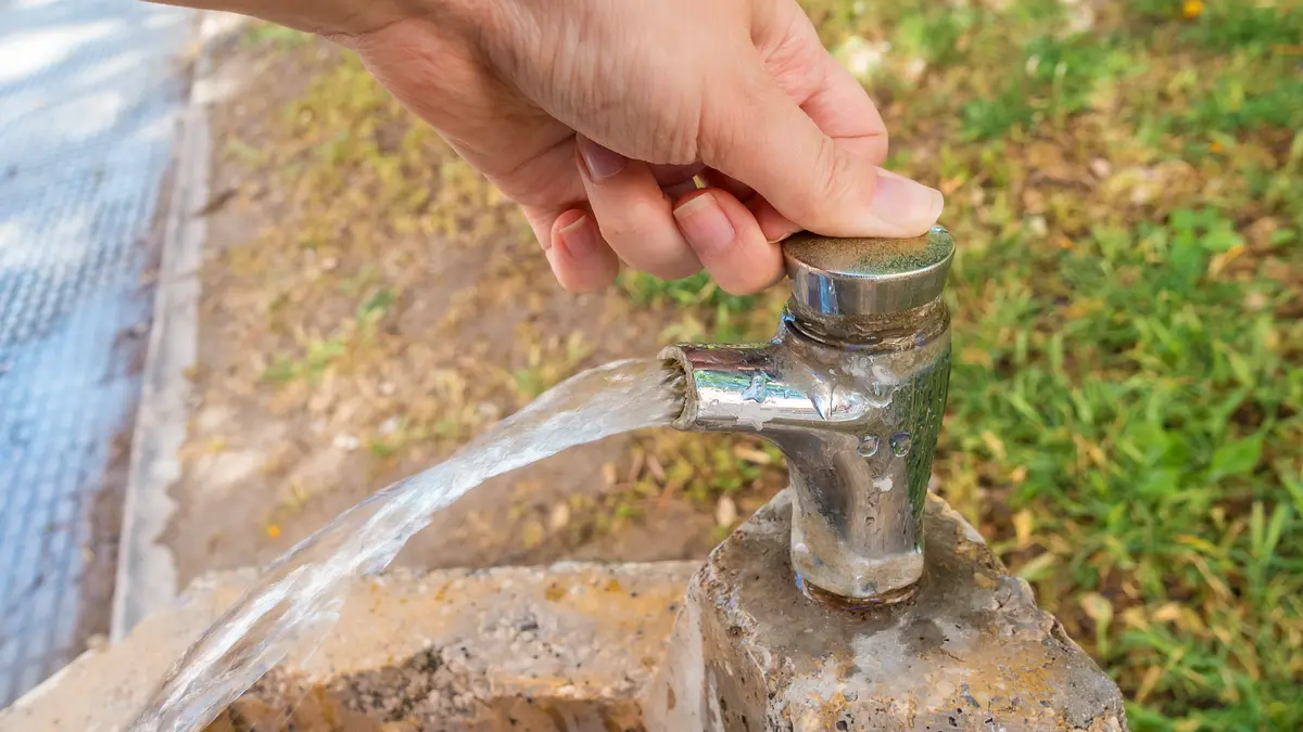 Frau bedient einen Trinkwasserbrunnen