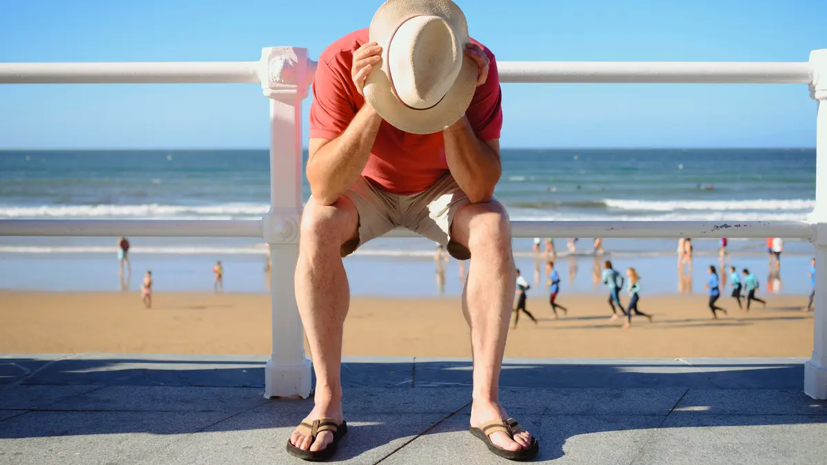 Mann stützt sich den Kopf auf die Hände am Strand