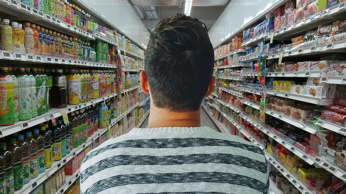 Mann im Supermarkt zwischen Regalen