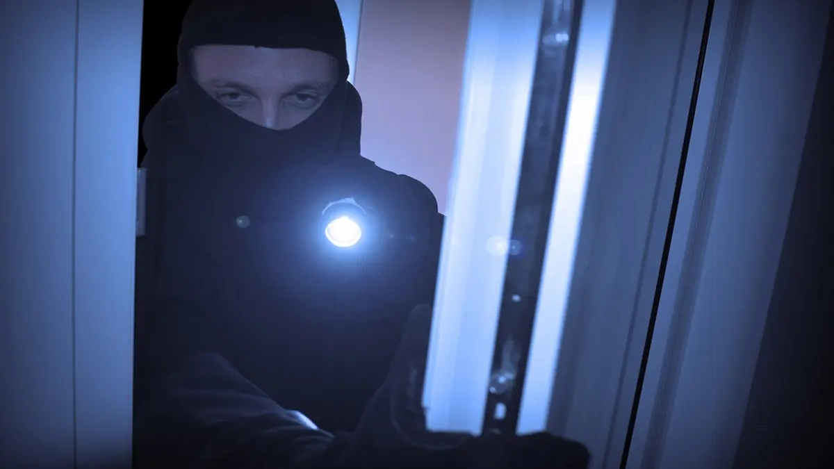 Mann bricht über ein Fenster in eine Wohnung ein.