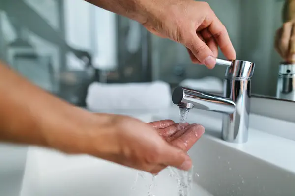 Person wäscht sich Hände unter Wasserhahn