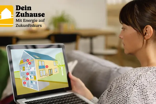 Frau sitzt am Laptop, auf dem ein Haus dargestellt wird