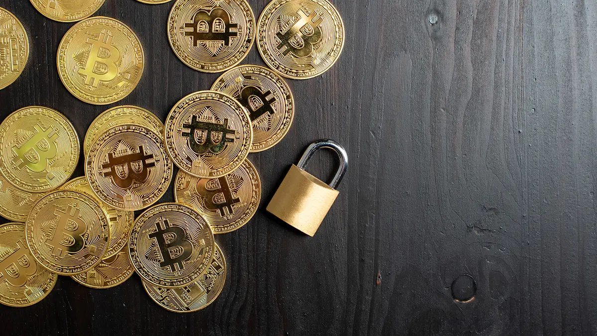 Bitcoin-Münzen und ein Vorhängeschloss auf schwarzer Tischplatte